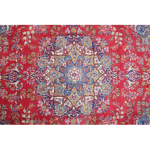 14 - A RED GROUND TABRIZ RUG with blue sunburst central medallion and blue spandrels on floral patterned ... 