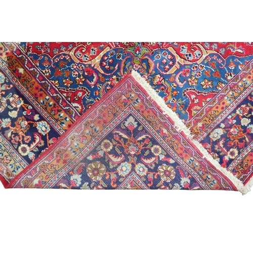 14 - A RED GROUND TABRIZ RUG with blue sunburst central medallion and blue spandrels on floral patterned ... 