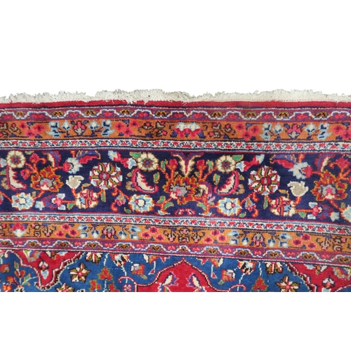 14 - A RED GROUND TABRIZ RUG with blue sunburst central medallion and blue spandrels on floral patterned ... 