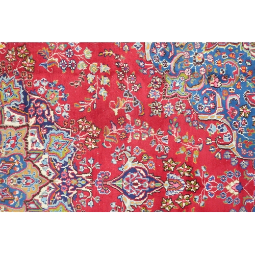 14 - A RED GROUND TABRIZ RUG with blue sunburst central medallion and blue spandrels on floral patterned ... 