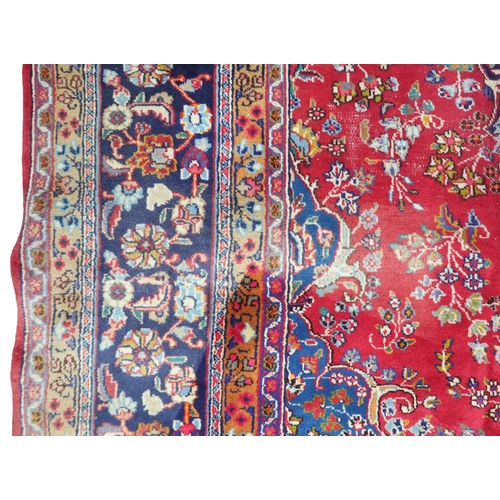 14 - A RED GROUND TABRIZ RUG with blue sunburst central medallion and blue spandrels on floral patterned ... 