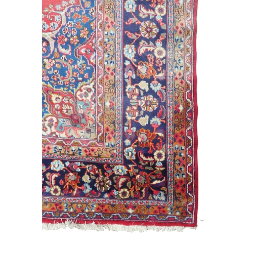 14 - A RED GROUND TABRIZ RUG with blue sunburst central medallion and blue spandrels on floral patterned ... 