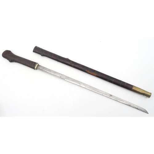 466 - A swagger stick, the scabbard and grip with imitation bark cladding a brass shell casing ferrule, th... 