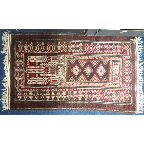 34 - A lot comprising a multicoloured geometric patterned prayer rug, 139cm long x 81cm wide and a red gr... 