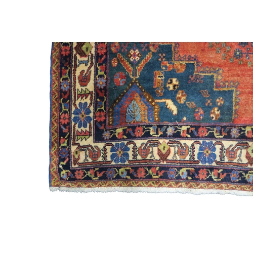 12 - A red ground Hamadan rug with dark blue geometric central medallion and matching spandrels on floral... 