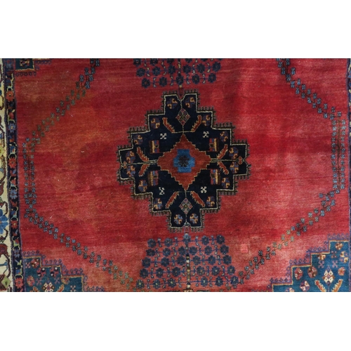 12 - A red ground Hamadan rug with dark blue geometric central medallion and matching spandrels on floral... 