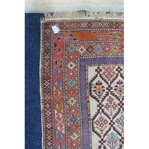 29 - A beige ground Caucasian rug with all over geometric floral patterned ground within multiple multico... 