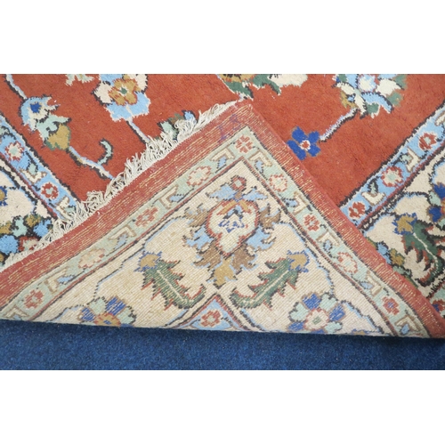 37 - A terracotta ground Zeigler style rug with floral/foliate patterned ground within cream floral borde... 