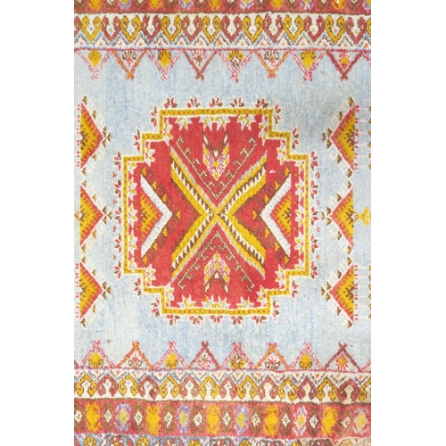 6 - A light blue ground Caucasian rug with red geometric central medallion on geometric patterned ground... 