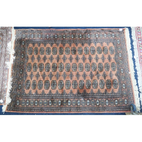 65 - A pink ground Bokhara style rug with all over lozenge design within dark lozenge border, 182cm long ... 