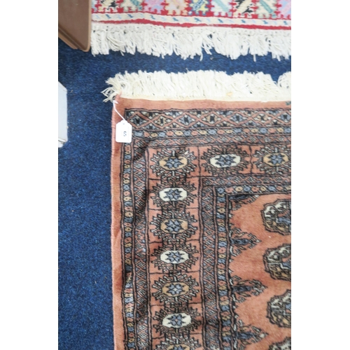 65 - A pink ground Bokhara style rug with all over lozenge design within dark lozenge border, 182cm long ... 