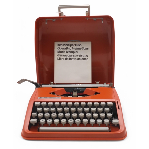 510 - A vintage Olivetti Hermes Baby portable typewriter, in coral red, retaining its original instruction... 