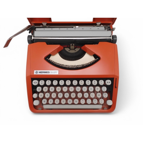 510 - A vintage Olivetti Hermes Baby portable typewriter, in coral red, retaining its original instruction... 