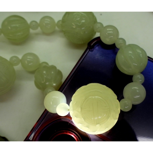 870 - A collection of Chinese green hardstone to include;- a string of pale green beads carved with symbol... 