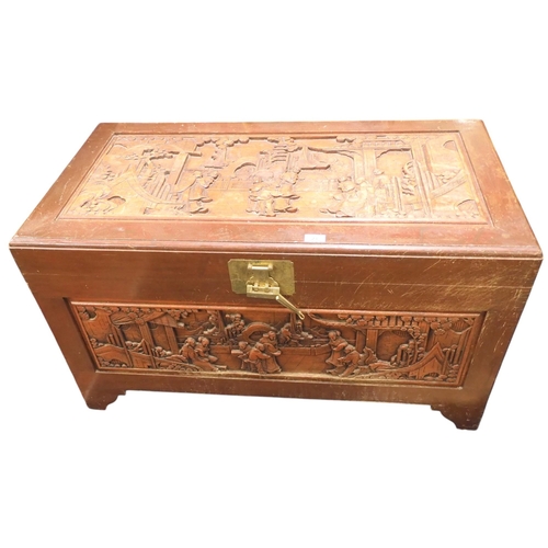 23 - An early 20th century Chinese hardwood blanket chest with carved top and front panels depicting vill... 