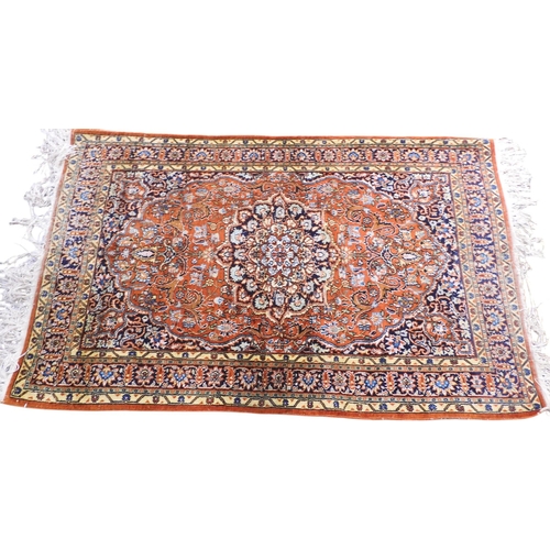 27 - A small burnt ochre Tabriz Kashmiri rug with dark blue central medallion and matching spandrels on e... 