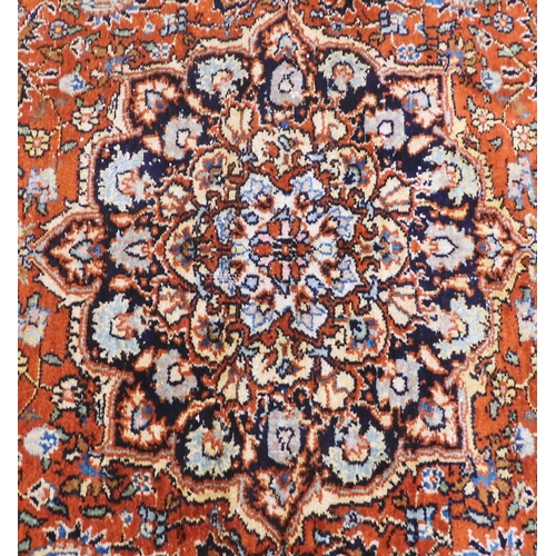 27 - A small burnt ochre Tabriz Kashmiri rug with dark blue central medallion and matching spandrels on e... 