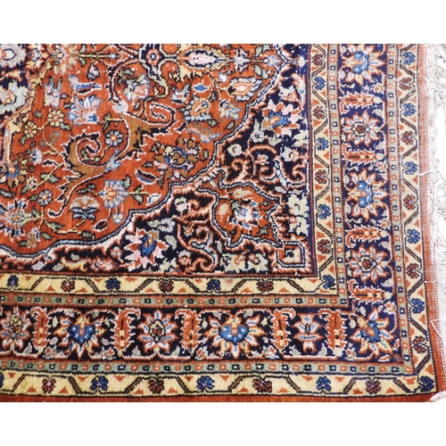 27 - A small burnt ochre Tabriz Kashmiri rug with dark blue central medallion and matching spandrels on e... 