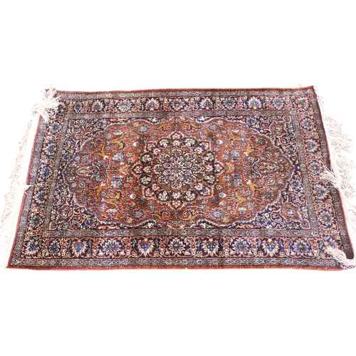 35 - A red ground Isfahan Kashmiri rug with multicoloured central medallion and matching spandrels on ext... 