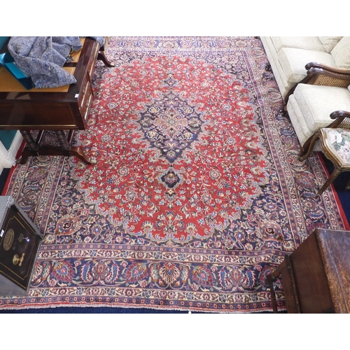 36 - A red ground Sabzevar rug with dark floral pattern central medallion and matching spandrels on flora... 