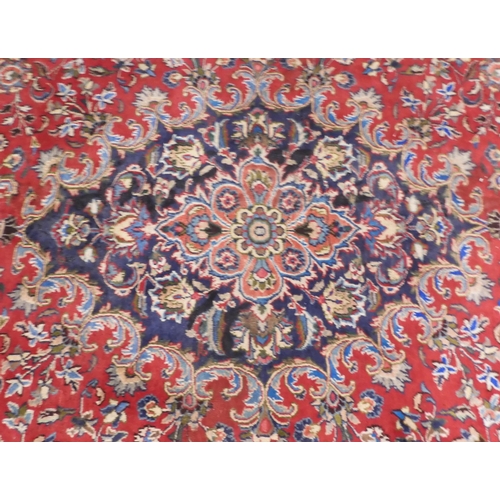 36 - A red ground Sabzevar rug with dark floral pattern central medallion and matching spandrels on flora... 