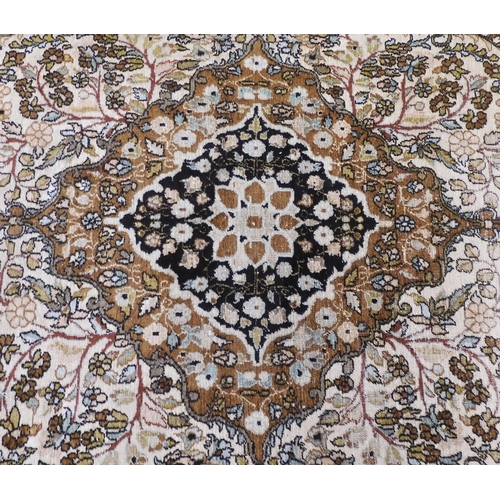 38 - A cream ground Keshan rug with earth tone central medallion and matching spandrels on floral pattern... 