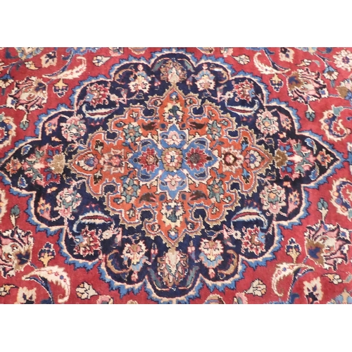 6 - A red ground Mashed rug with dark blue central medallion and matching spandrels on floral patterned ... 