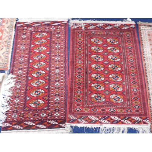 67 - A lot comprising a red ground Bokhara style rug with all over lozenge design within geometric border... 