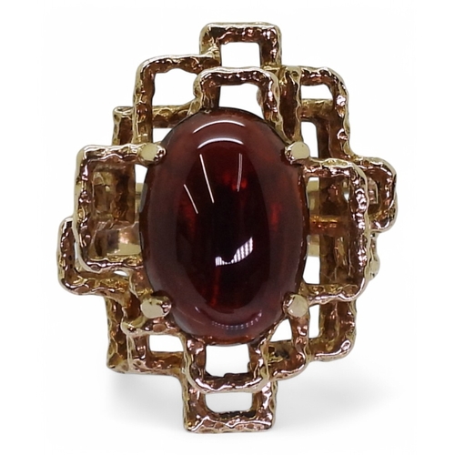 2755 - A RETRO GARNET RINGset with an oval garnet cabochon of approx 14mm x 10mm x 4.5mm, the ring has full... 