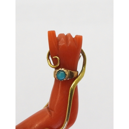 2787 - A SYMBOLIC CORAL BROOCHthe coral carved in the shape of an arm with two fingers extended in a symbol... 