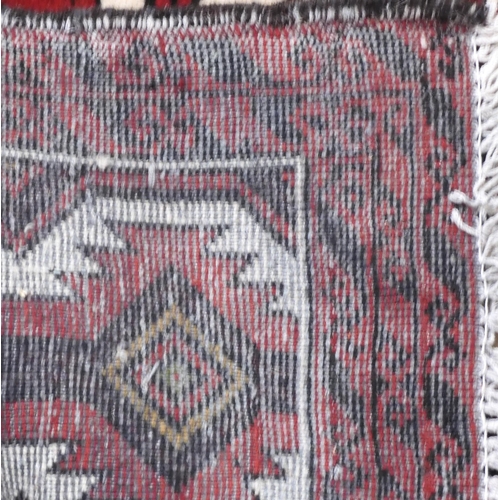 121 - A white ground Baluch rug with dark red geometric ground within red border, 175cm long x 92cm wide