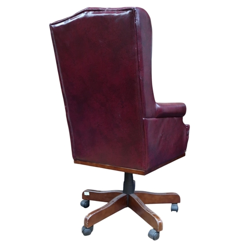 2 - A 20th century red leatherette button upholstered swivel desk chair with wing back over scrolled arm... 