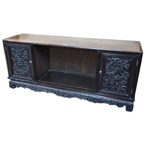 23 - An early 20th century Chinese elm sideboard with central open compartment flanked by extensively car... 