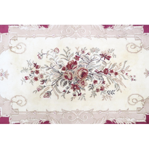 55 - A red ground Aubusson style rug with cream floral patterned central panel within cream floral scroll... 