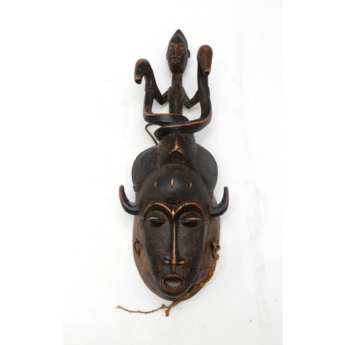 2277 - A SENOUFO MASKCarved and detailed with a figure holding two serpents above combed hair and scored fa... 