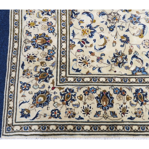 2125 - AN IVORY GROUND KASHAN FINE PILE WOOL RUGwith all over floral/foliate patterned ground within flower... 