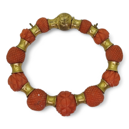 2796 - A CORAL BRACELETeach bead carved with alternate cross hatched pattern or foliate forms, with gold pl... 