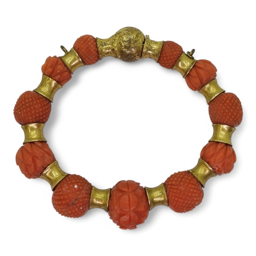 2796 - A CORAL BRACELETeach bead carved with alternate cross hatched pattern or foliate forms, with gold pl... 