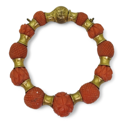 2796 - A CORAL BRACELETeach bead carved with alternate cross hatched pattern or foliate forms, with gold pl... 