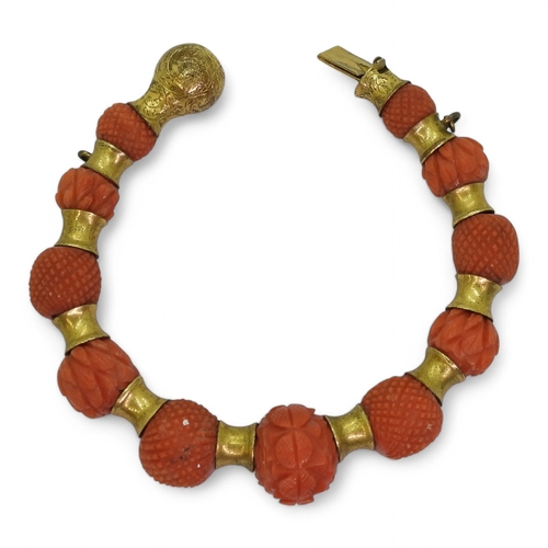 2796 - A CORAL BRACELETeach bead carved with alternate cross hatched pattern or foliate forms, with gold pl... 