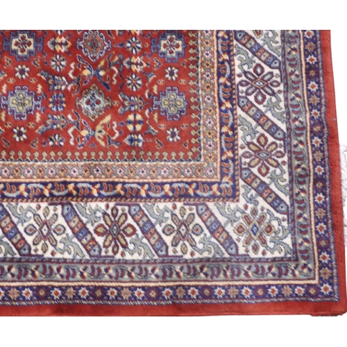 17 - A red ground Persian style rug with all over geometric floral patterned ground within dark blue and ... 