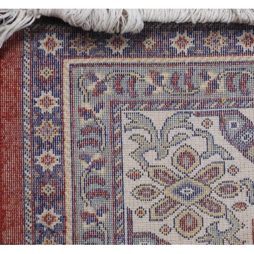 17 - A red ground Persian style rug with all over geometric floral patterned ground within dark blue and ... 