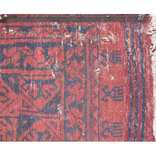 35 - A large red ground vintage Afghan rug with dark geometric patterned ground within geometric patterne... 