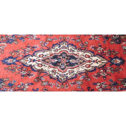 6 - A red ground Hamadan rug with cream and blue central medallion and matching spandrels on floral patt... 