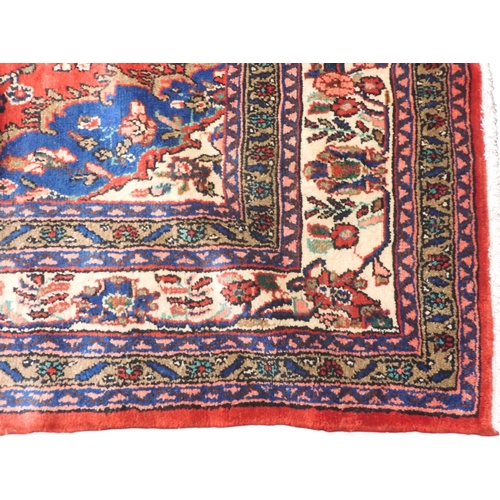 6 - A red ground Hamadan rug with cream and blue central medallion and matching spandrels on floral patt... 