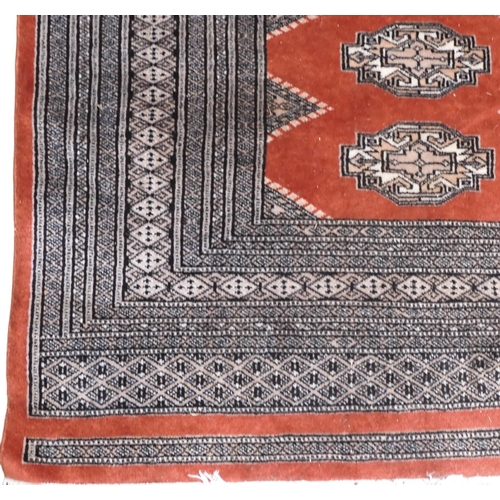 8 - A terracotta ground Bokhara style rug with cream and beige lozenge patterned ground within multiple ... 