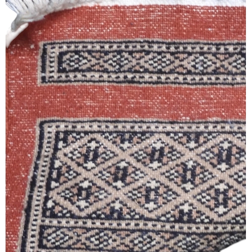 8 - A terracotta ground Bokhara style rug with cream and beige lozenge patterned ground within multiple ... 