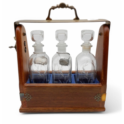 162 - A three bottle tantalus with brass mounts