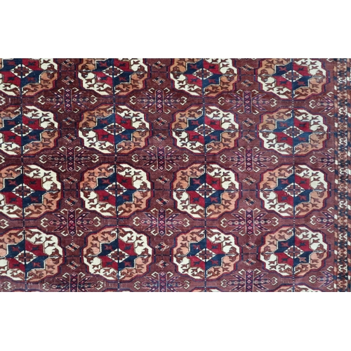 4 - A ochre ground antique Turkoman rug with all-over multicoloured lozenge patterned ground within mult... 