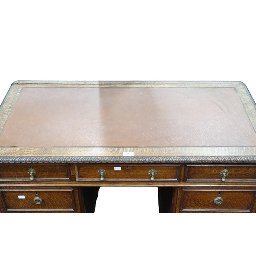 5 - A late 19th/early 20th century oak pedestal writing desk with brown skiver top with gadrooned edge o... 